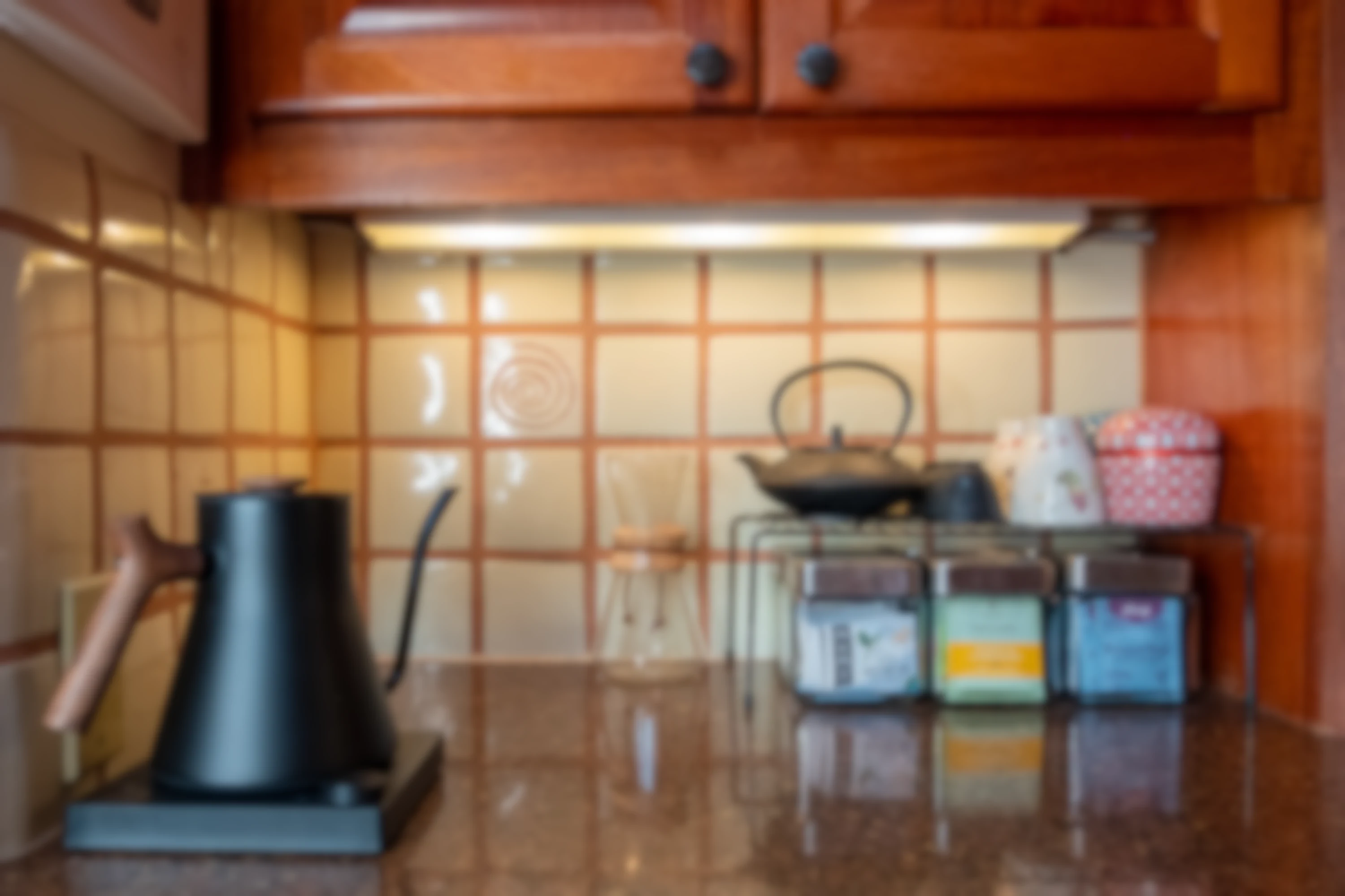 A background image showing a clean kitchen area, with teabags, teaware, and a kettle